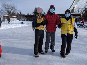 Deux accompagnatrices assistent un participant en patin.