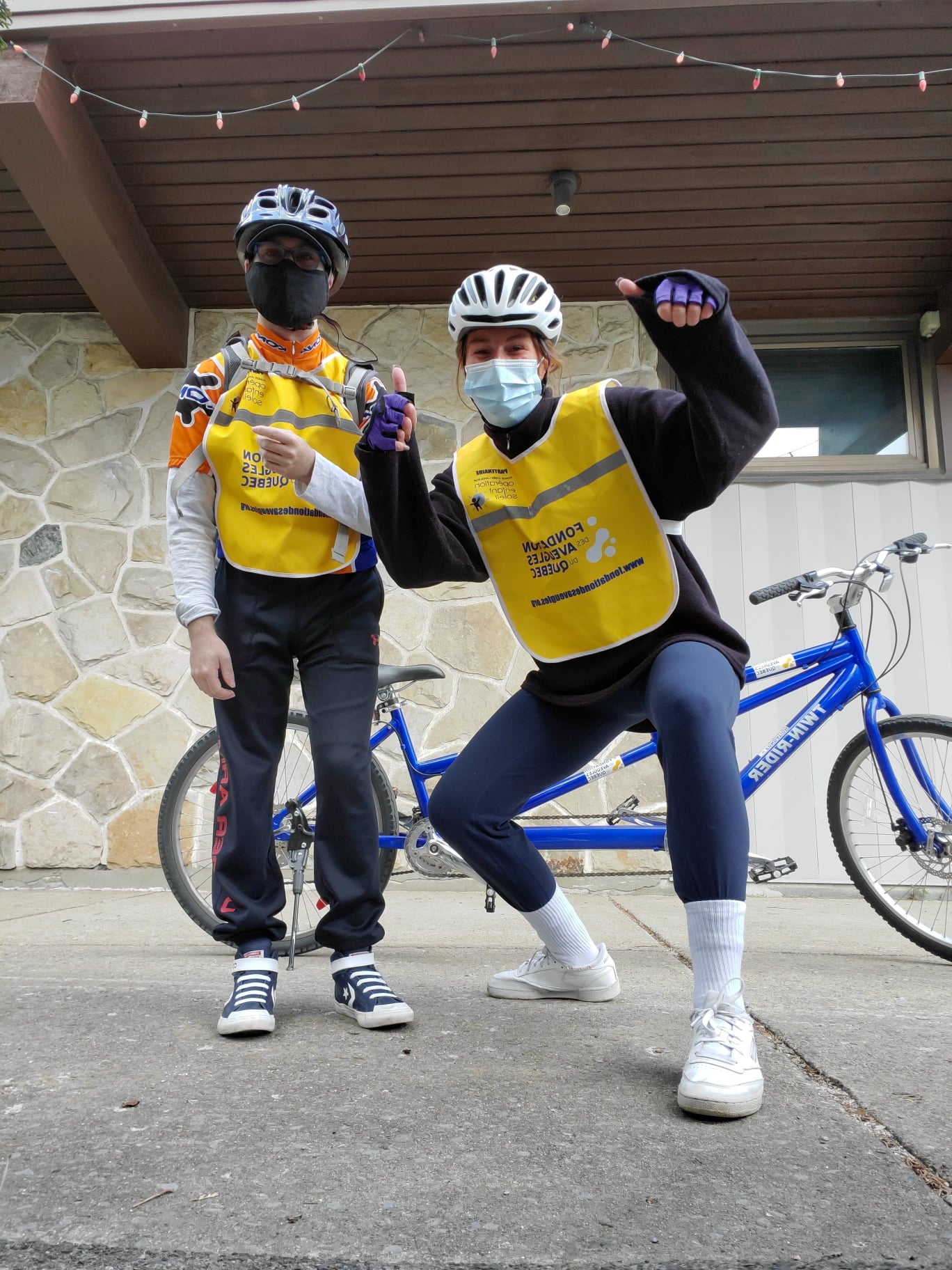 Un égo portrait d’une accompagnatrice avec les pouces levés et un participant. Un vélo-tandem est visible en arrière-plan.