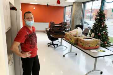 Description de l'image: Photo de monsieur Sylvain Beaudoin devant une table remplie de denrées prêtes a être distribuées à nos locataires.