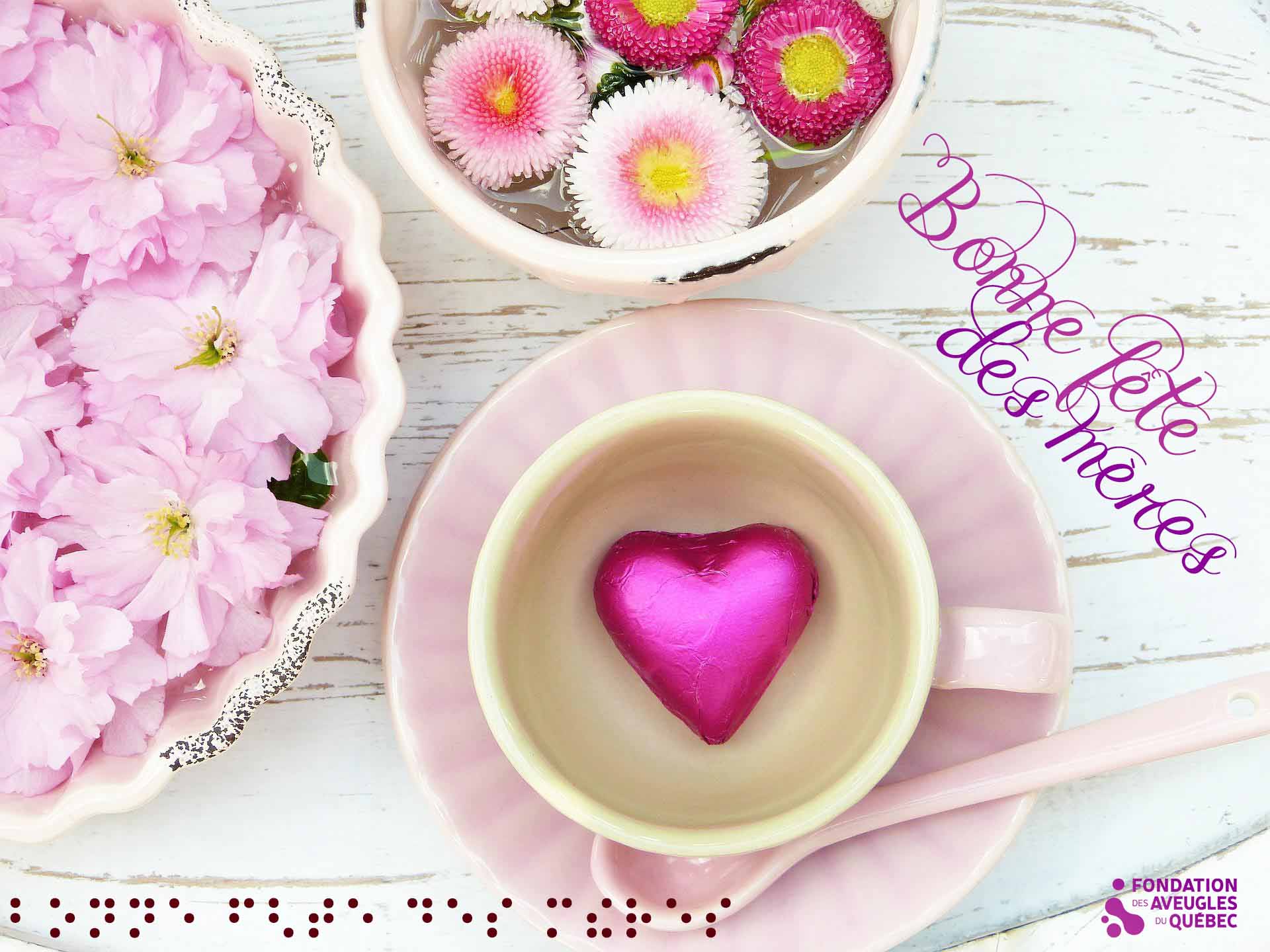 Montage visuel portant la mention Bonne fête des mères en écriture de fantaisie et en braille. Deux grands bols remplis de fleurs et une tasse avec un cœur à l'intérieur.