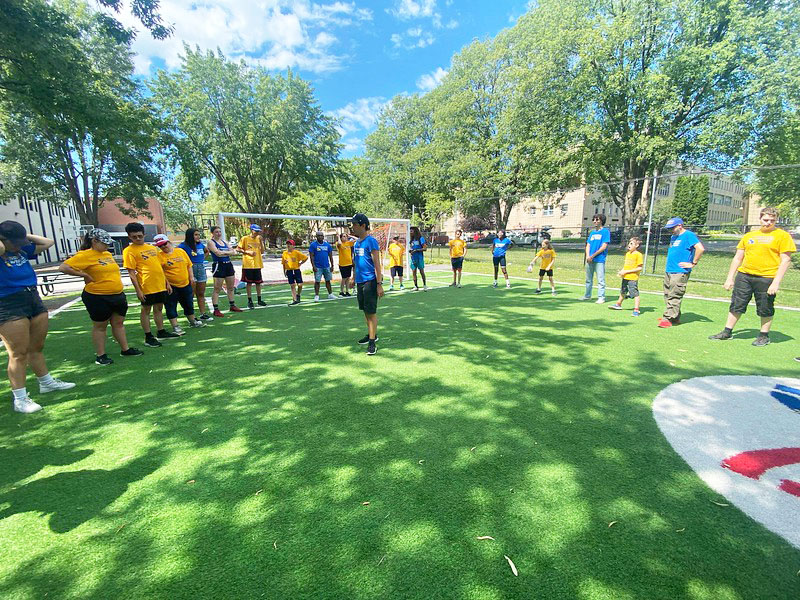 Les participants forment un énorme cercle sur un terrain de soccer pour une activité lors du BBQ du Directeur.